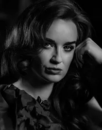 En närbild på en kvinnas ansikte, hon lutar huvudet mot sin vänstra hand.