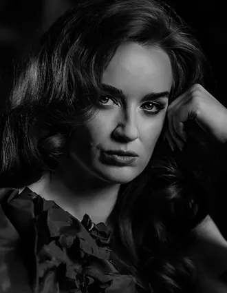 En närbild på en kvinnas ansikte, hon lutar huvudet mot sin vänstra hand.