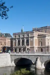 Stora byggnader mot en blå himmel, i förgrunden ett vattendrag.