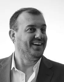 En närbild på en man med ett stort leende, han blickar ut mot höger.