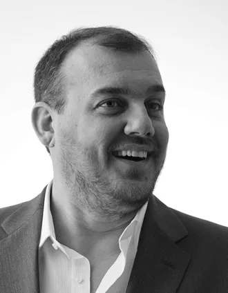 En närbild på en man med ett stort leende, han blickar ut mot höger.