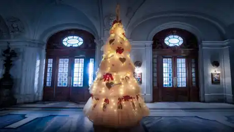 En julgran av tyll och med tåskor i en pampig hall.