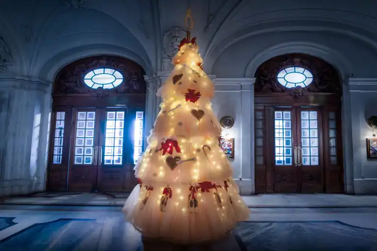 En julgran av tyll och med tåskor i en pampig hall.