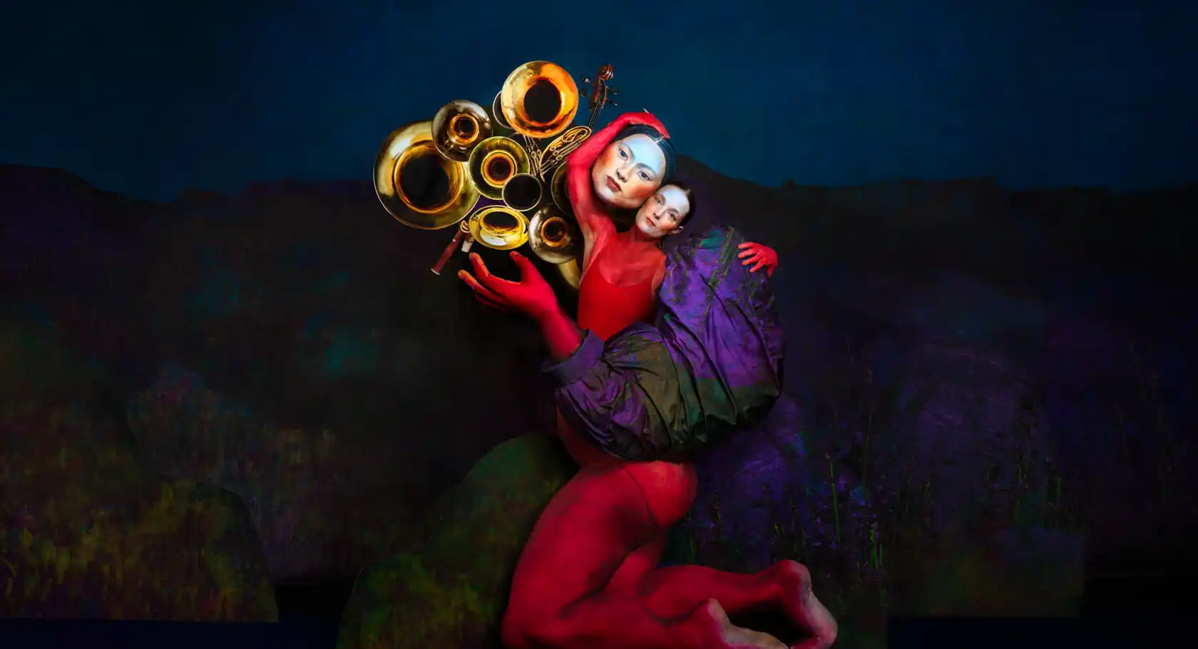 A woman appears in the middle of a large doll figure, on the left several trumpets.