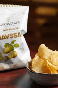 En skål med chips och en chipspåse på ett bord.