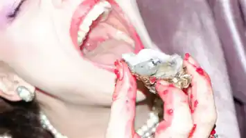 Närbild på en kvinna med kladdiga händer som för ett ostron mot sin mun.