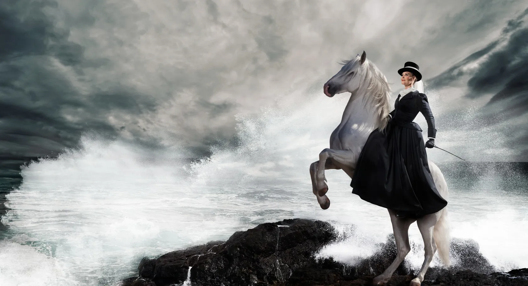 A woman riding a white horse on top of a rocky cliff.