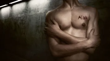 Den nakna torson av en ung man med namnet Aida inristat på bröstet.