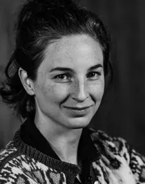 En närbild på en kvinna med mörkt hår: hon bär en mönstrad stickad kofta.