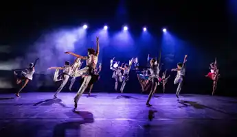 Flera dansare rör sig synkroniserat på en scen.