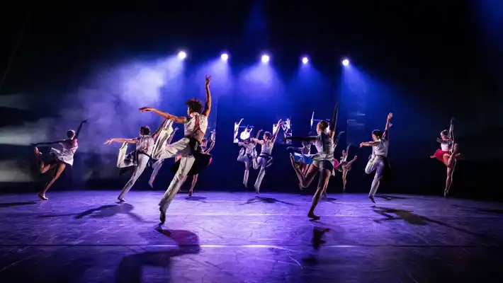 Flera dansare rör sig synkroniserat på en scen.