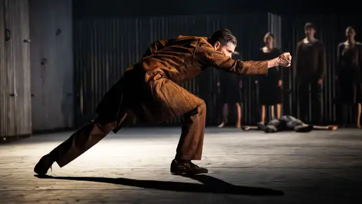 A man in a brown suit is dancing.