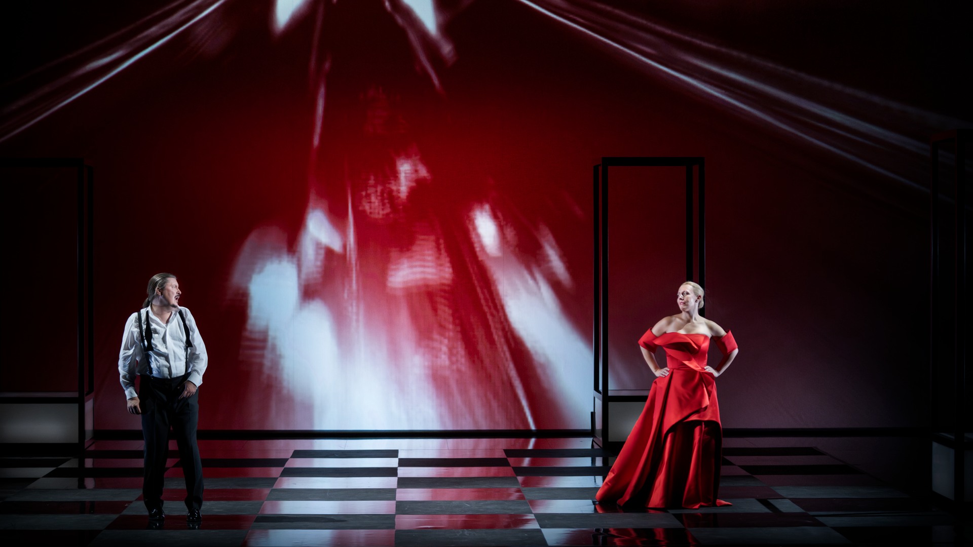 En kvinna i magnifik röd klänning, i bakgrunden en man.