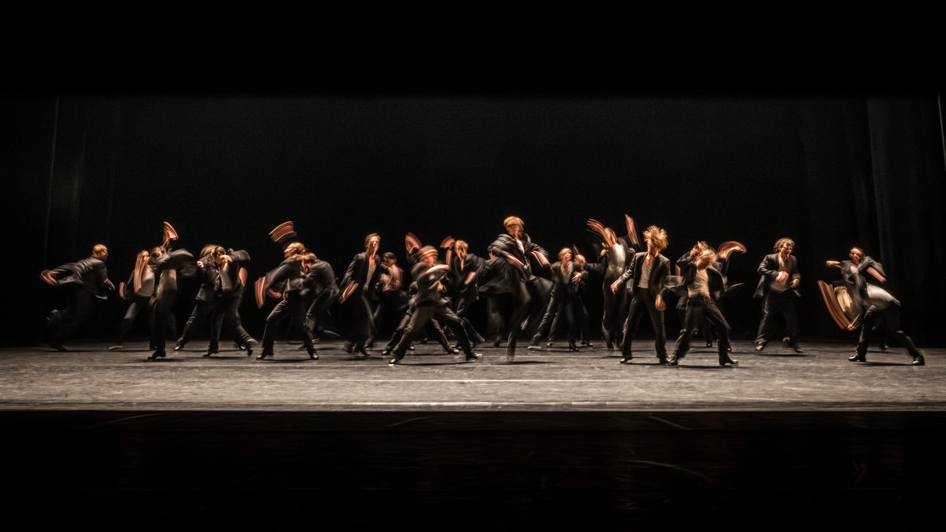 En stor mängd dansare rör sig energiskt på en scen.