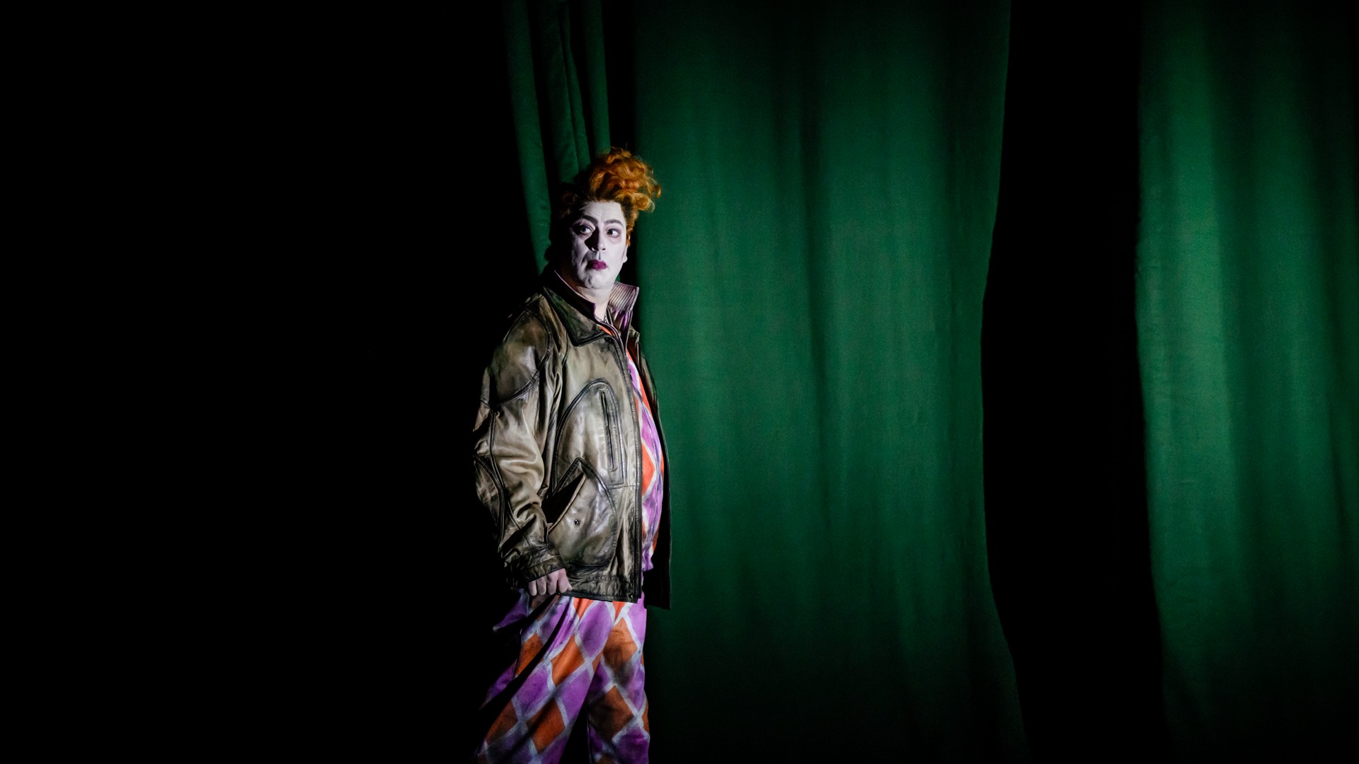 En man står framför en grön fond.