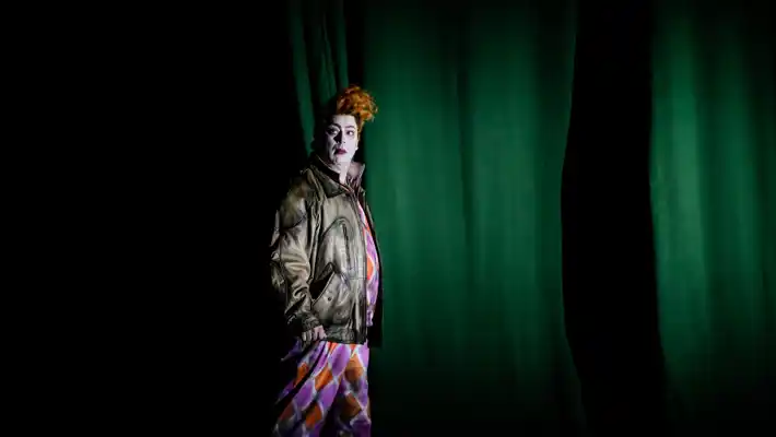 En man står framför en grön fond.