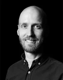 Närbild på en leende, skäggprydd man.