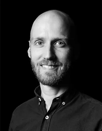 Närbild på en leende, skäggprydd man.