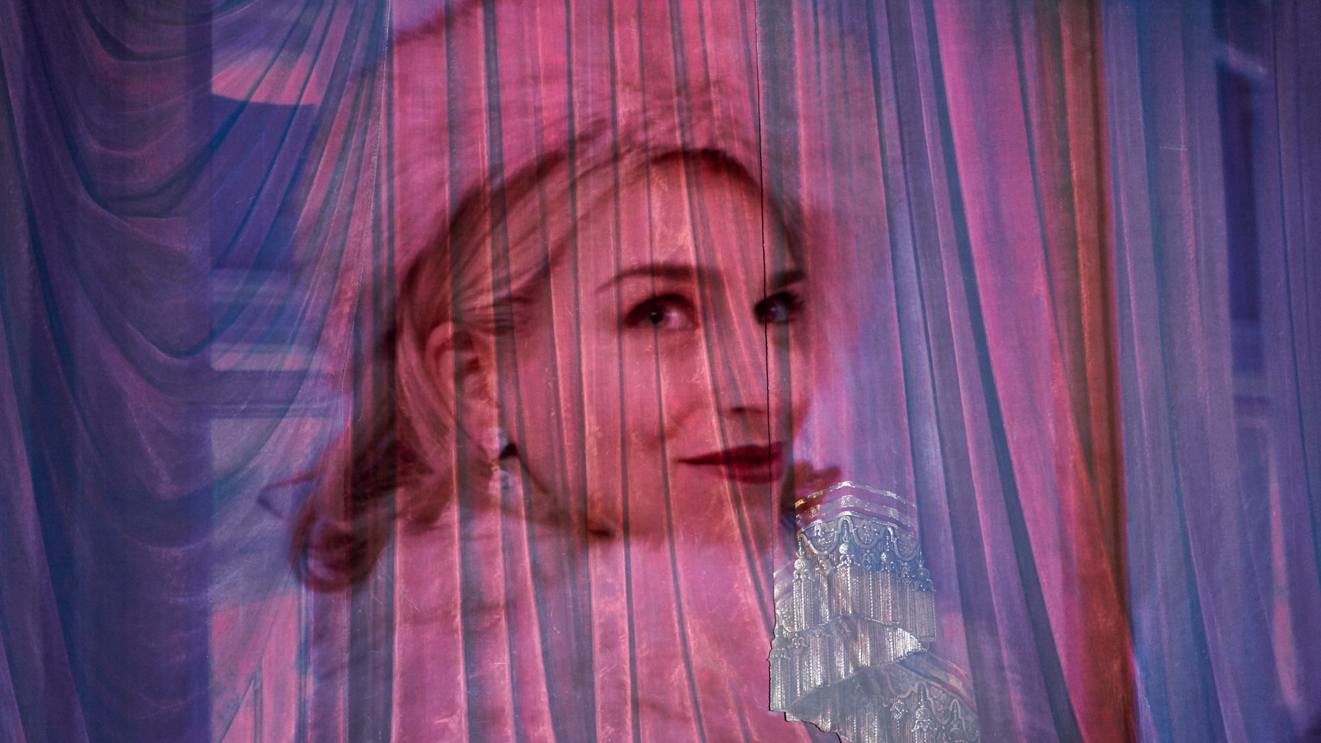 A woman in a fur hat is projected onto a curtain.