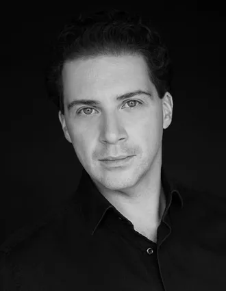 En närbild på en man med lätt uppknäppt mörk skjorta.