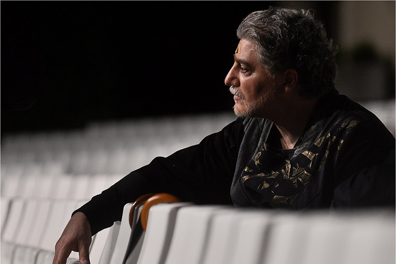 En man i profil som vilar sina armar mot stolsryggar.