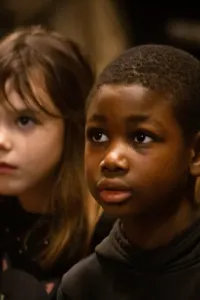 A photo of children in an indoor environment. The children wear colorful clothes and seem engaged in an activity.