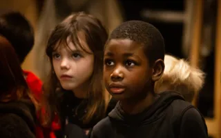 Ett foto av barn i en inomhusmiljö. Barnen bär färgglada kläder och verkar engagerade i en aktivitet.