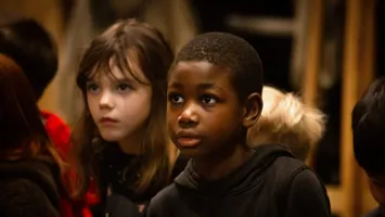 Ett foto av barn i en inomhusmiljö. Barnen bär färgglada kläder och verkar engagerade i en aktivitet.