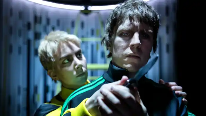 En man står bakom en annan man och håller upp en kniv framför dennes ansikte.