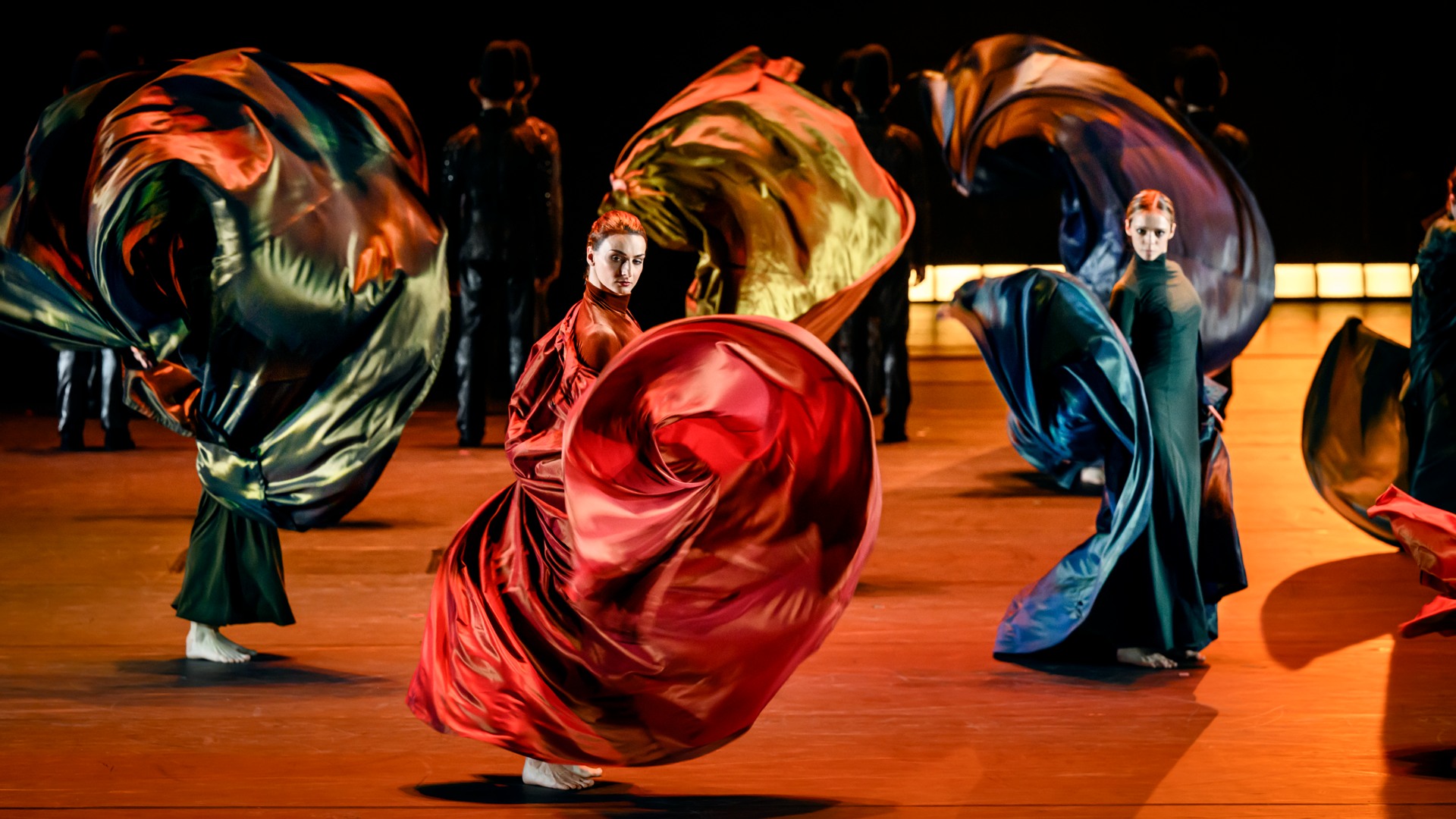 Flera kvinnor i klänningar sätter tyg i effektfull rörelse.