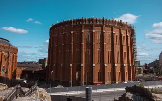 A cylindrical brick building without a roof in the middle of a construction site.