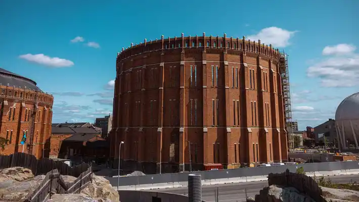 A cylindrical brick building without a roof in the middle of a construction site.