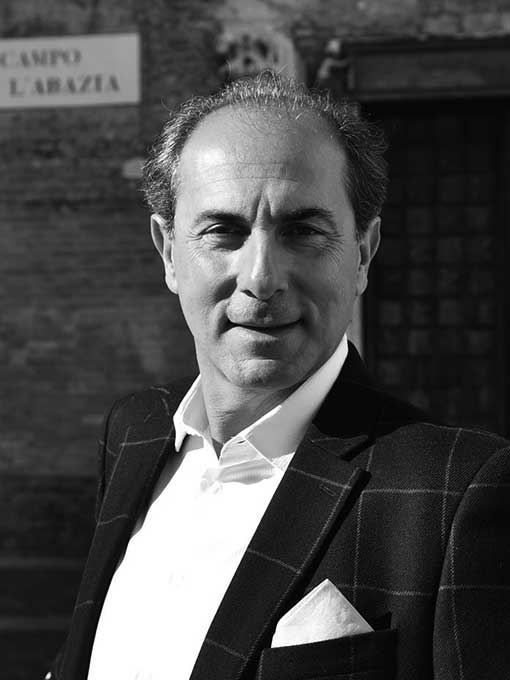 A close-up of a smiling man in a checkered suit.