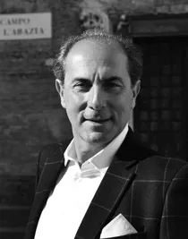 A close-up of a smiling man in a checkered suit.