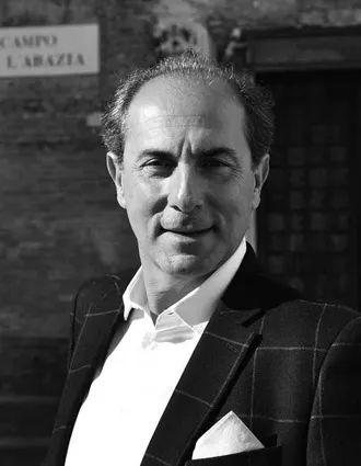 En närbild på en leende man i rutig kostym.