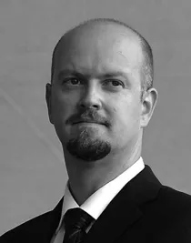 Porträttbild av en man klädd i kostym och med slips.