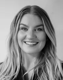 En leende kvinna med långt blont hår ler mot kameran.