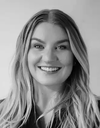 En leende kvinna med långt blont hår ler mot kameran.