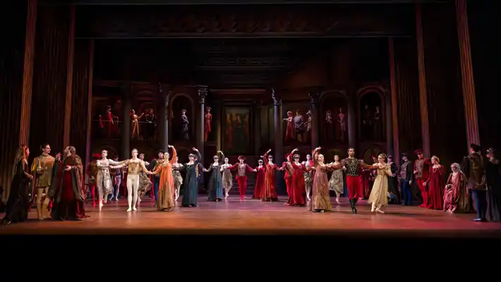 En stor mängd dansare står på en scen i olika poser.