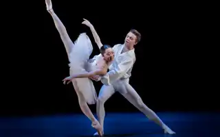 A pas de deux with a male and a female dancer in white costumes.