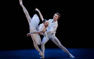 A pas de deux with a male and a female dancer in white costumes.