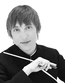 En närbild av en korthårig kvinna som i handen håller en dirigentpinne.