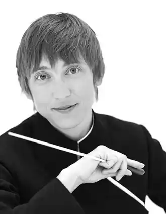 En närbild av en korthårig kvinna som i handen håller en dirigentpinne.