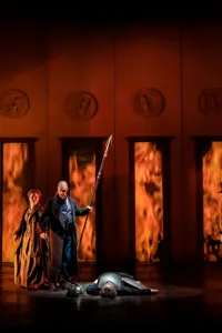 En grupp människor som står på en scen, eld i bakgrunden.