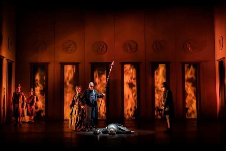 En grupp människor som står på en scen, eld i bakgrunden.