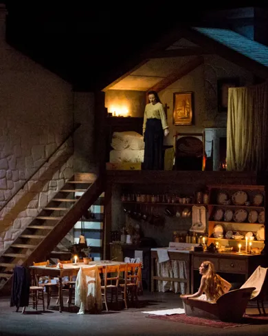 En scenbild med ett stort hus som liknar ett dockskåp: på övervåningen står en kvinna, i golvplanet sitter en kvinna i ett badkar.