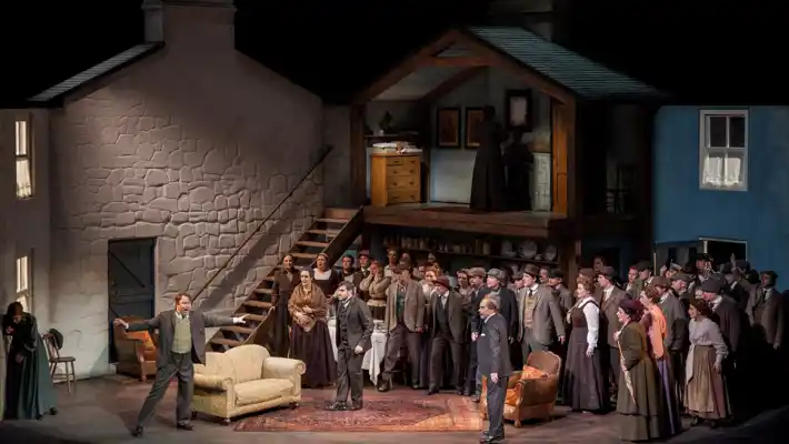 A scene with buildings in the background, in the foreground a large group of people.