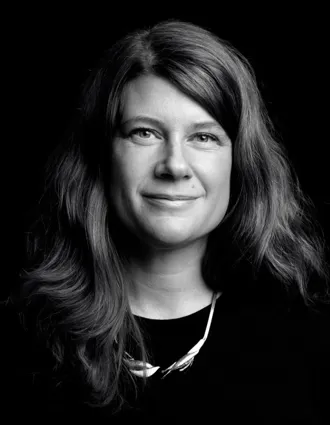 A close-up of a woman with flowing dark hair and a distinctive necklace.