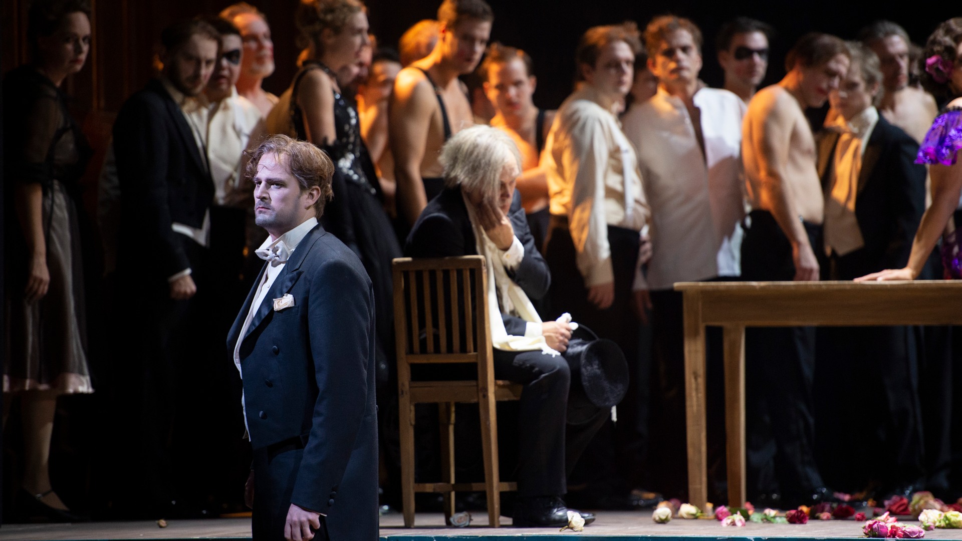 A sad man in a suit stands in front of a large crowd.