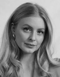 En närbild på en kvinna med långt blont hår: hon bär en ljus kavaj.